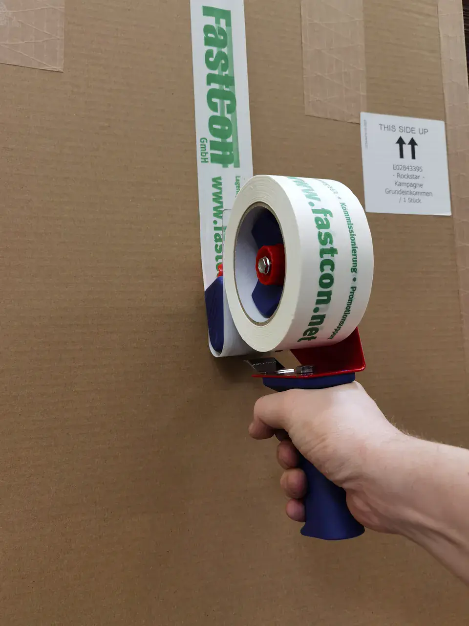 Karton wird von Hand mit FastCon-Klebeband verschlossen